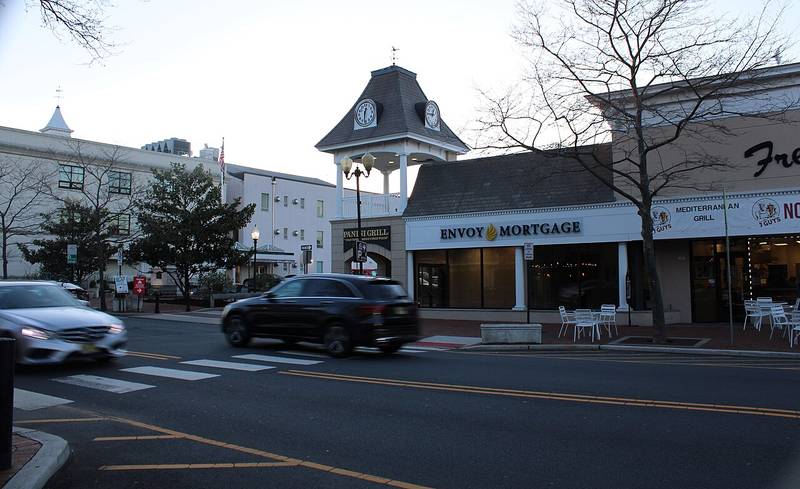 A clock tower and storefronts on a street in downtown Freehold Borough