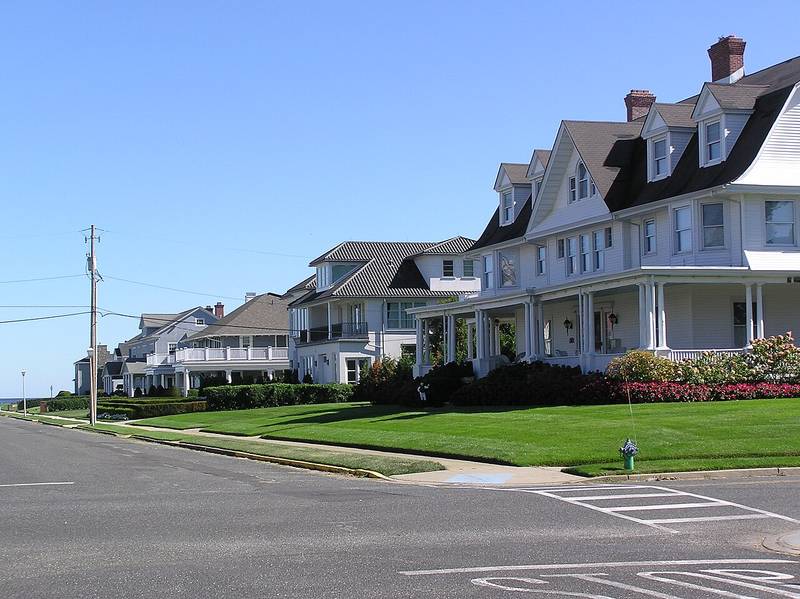 Large historic homes with porches along a street leading to the ocean in Allenhurst, New Jersey