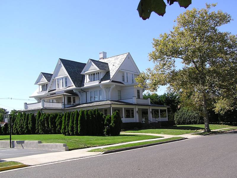 A large white Shingle-style home with a wraparound porch in the Allenhurst Residential Historic District